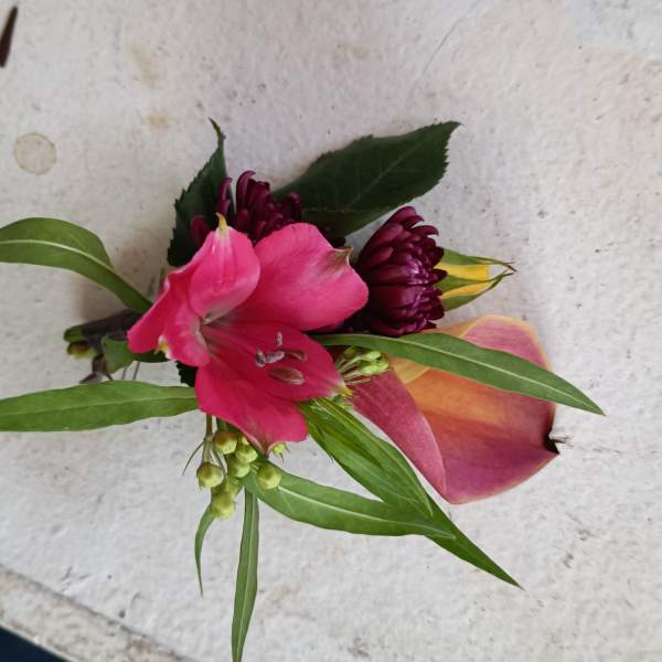 Small boutonniere with pink and burgundy flowers and a calla lily