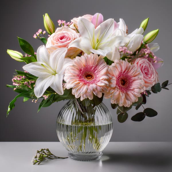 Pink roses and white lilies in a clear glass vase