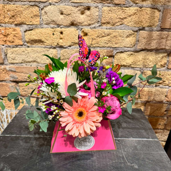 Pink and white mixed bouquet in a bright pink gift box with a butterfly topper