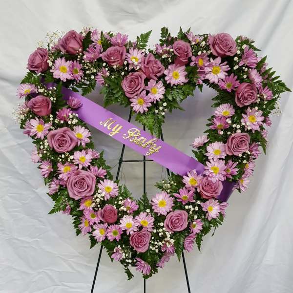 Heart-shaped floral wreath with pink roses and daisies on a purple ribbon