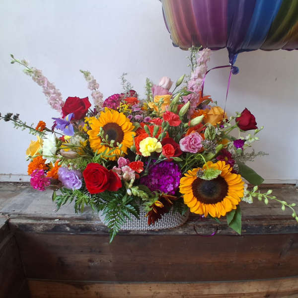 Colorful mixed flower arrangement with sunflowers and roses in a woven basket