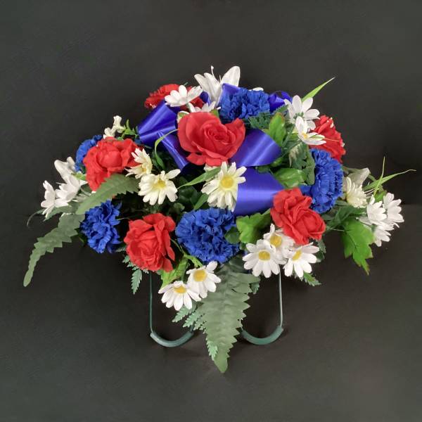 Red, white, and blue floral arrangement with a purple ribbon on a stand