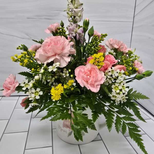 Pink and white floral arrangement in a white container