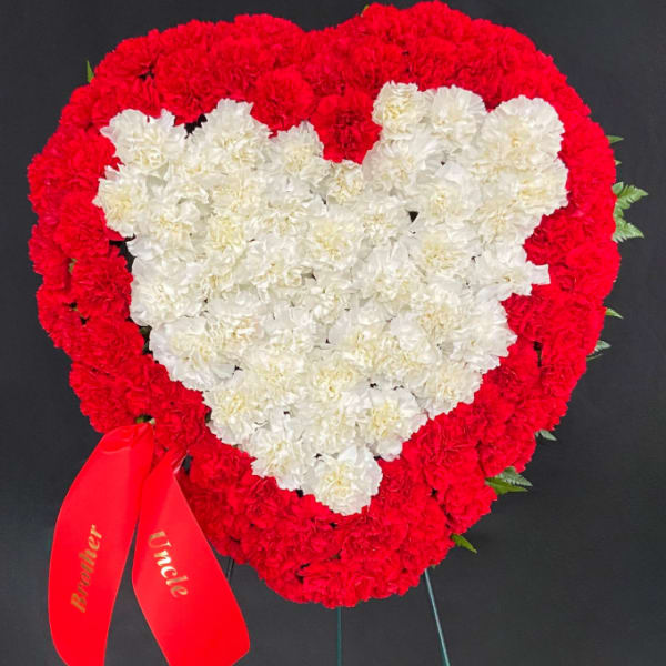 Heart-shaped red and white carnation wreath with a red ribbon