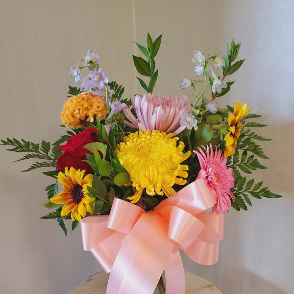 Mixed bouquet of bright flowers tied with a pink ribbon
