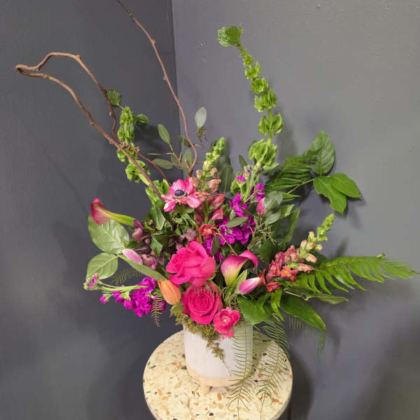 Bright pink and purple floral arrangement in a white vase