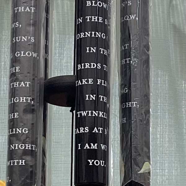 Hanging black wind chimes with floral accents and a small wooden tag