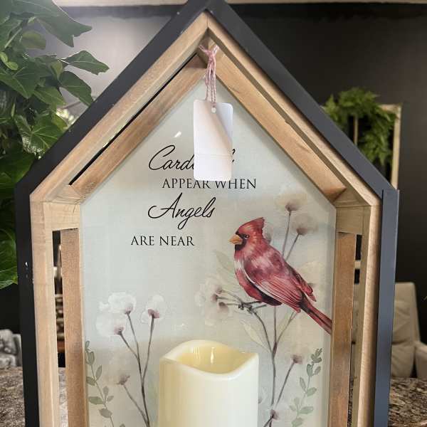 House-shaped memorial lantern with a candle and cardinal artwork