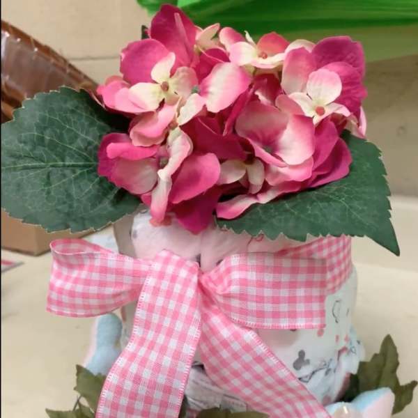 Pink hydrangea arrangement in a decorative container with a gingham ribbon