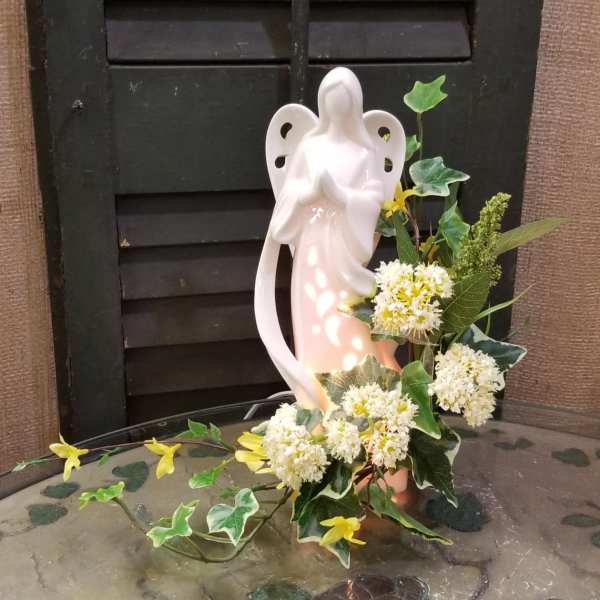 Ceramic angel figurine with white and yellow flowers and ivy