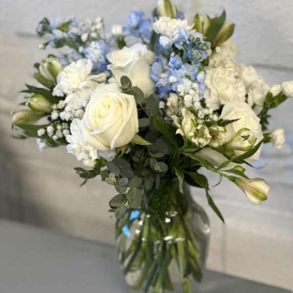 White roses and blue flowers in a glass vase