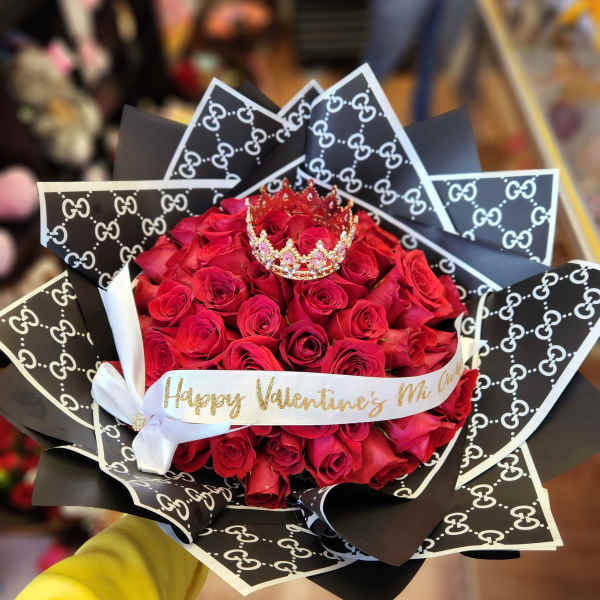 Bouquet of red roses with a small crown and patterned black wrapping