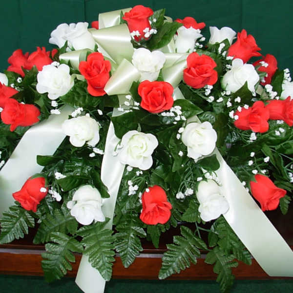 Red and white rose arrangement with satin ribbons on a casket
