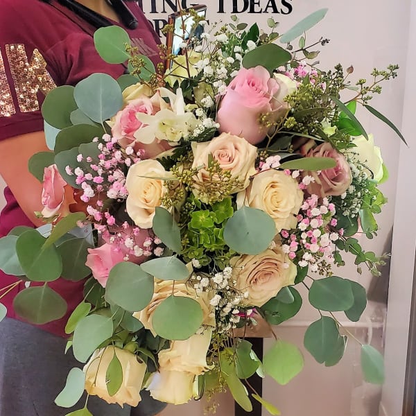 Handheld bouquet of pink and cream roses with eucalyptus and baby's breath