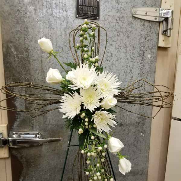 White floral cross arrangement on an easel with roses and spider mums