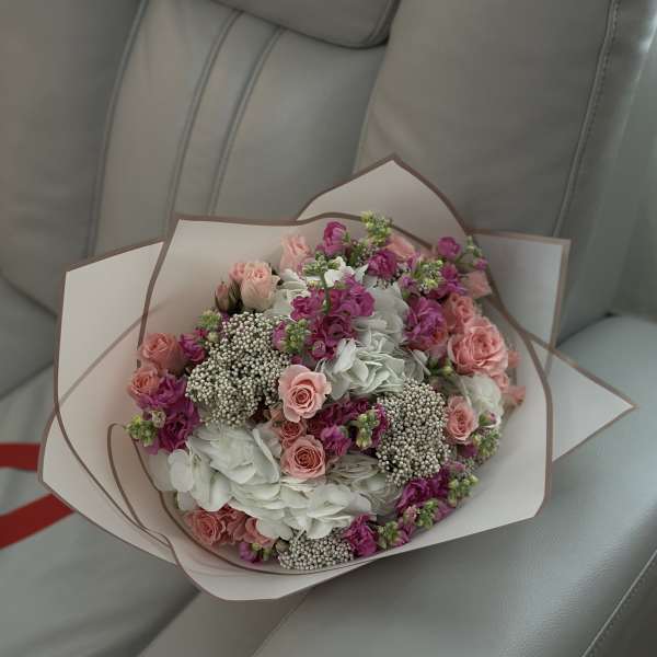 Bouquet of pink roses and white hydrangeas wrapped in pale paper