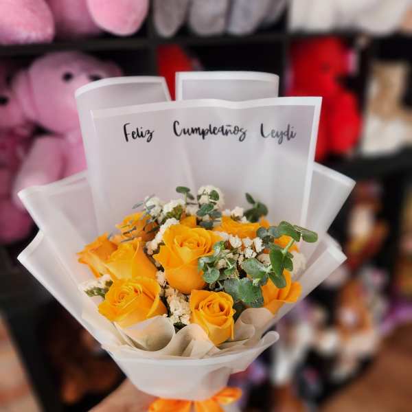 Bouquet of yellow roses wrapped in white paper with an orange ribbon