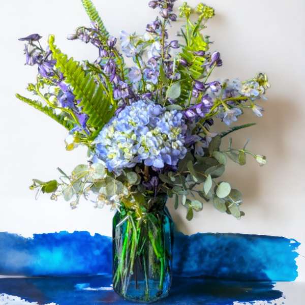 Blue and purple flower arrangement in a glass vase