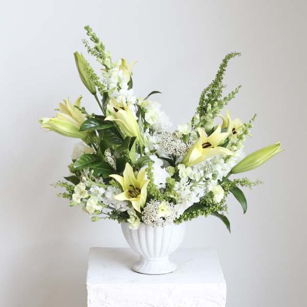White and pale yellow lily arrangement in a white vase
