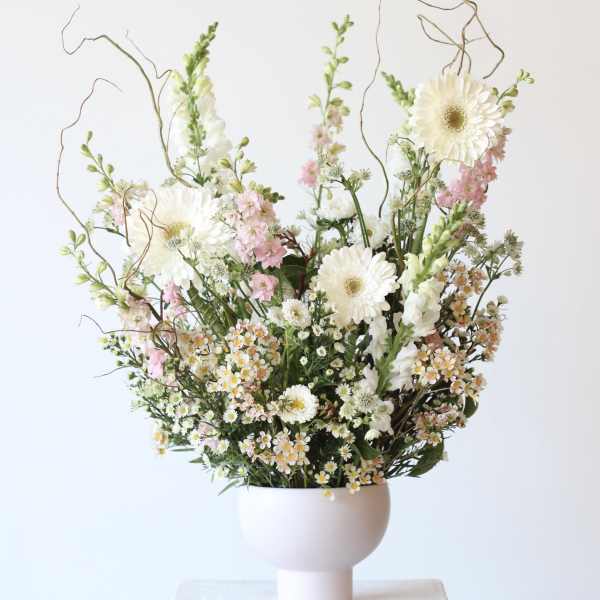 Tall bouquet of white and pink flowers in a pale vase