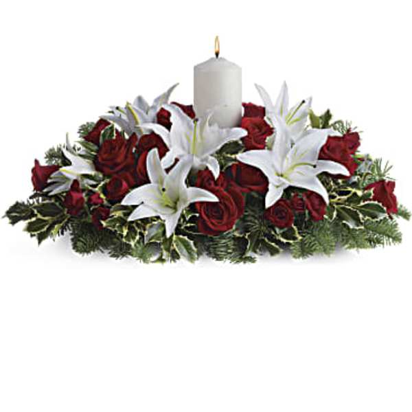 Red roses and white lilies arranged around a white candle