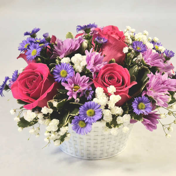 Pink roses and purple daisies in a white basket