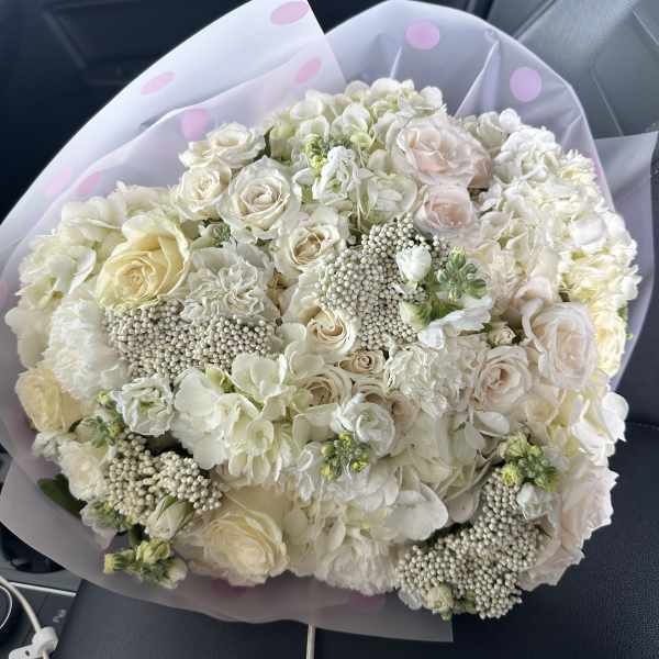 Large bouquet of white and blush roses with hydrangeas in lavender wrap