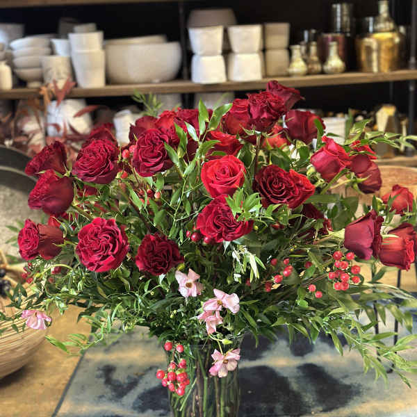 Red roses and pink accent flowers in a clear glass vase