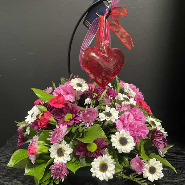 Pink and white flower arrangement with a red heart ornament