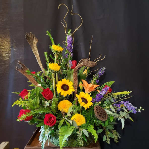 Tall floral arrangement with sunflowers, red roses, and orange lilies