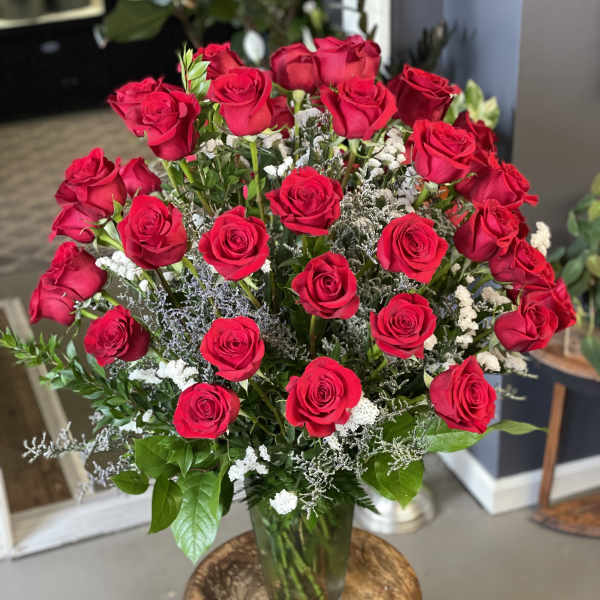 Bouquet of red roses in a glass vase with white filler flowers