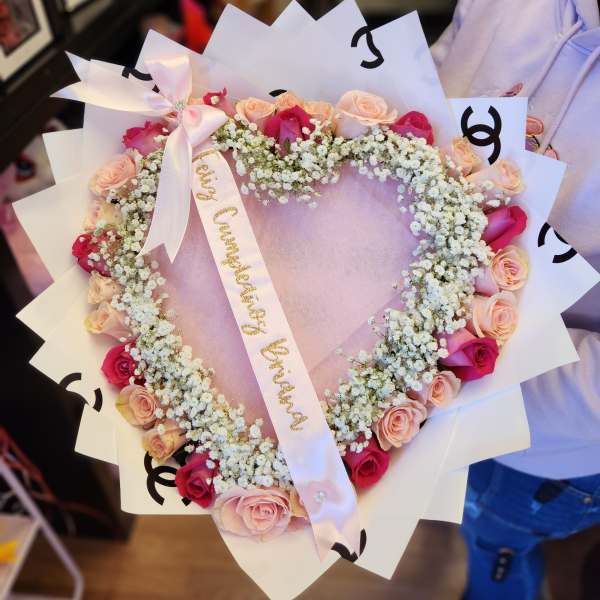 Heart-shaped bouquet of pink and peach roses with white baby's breath