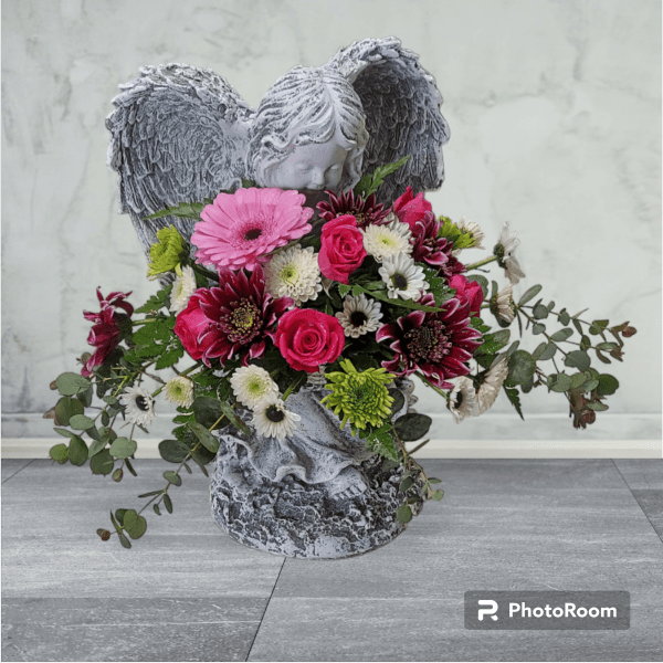 Stone angel figurine holding a mixed pink and white flower arrangement with roses and mums.