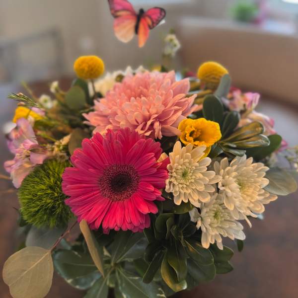 Mixed bouquet with pink and white daisies and a butterfly pick