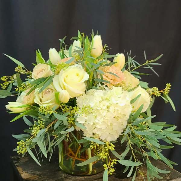 White roses and hydrangea in a glass vase with greenery
