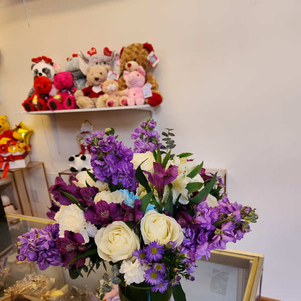 Mixed bouquet of white roses and purple flowers in a glass vase