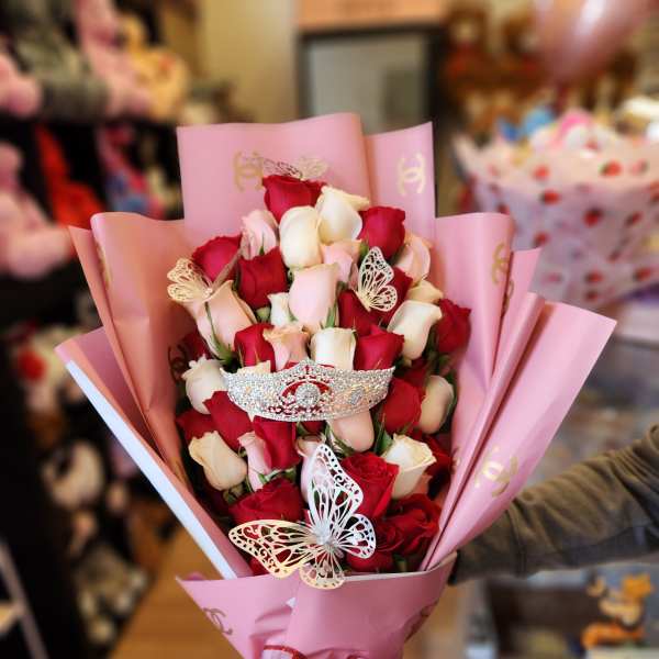 Bouquet of red and white roses wrapped in pink paper with a heart ribbon