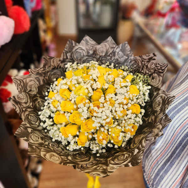 Bouquet of yellow roses with white baby's breath in patterned wrap