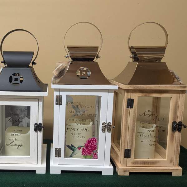 Four memorial lanterns with printed sympathy messages and bird artwork
