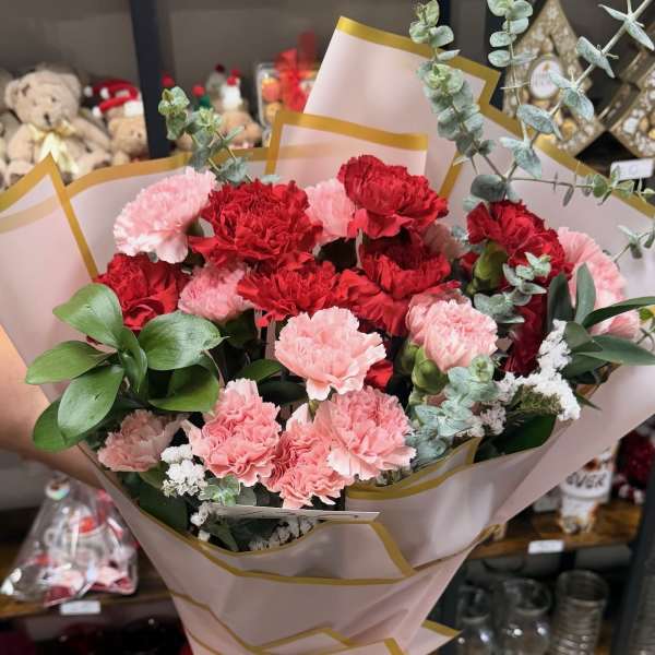 Bouquet of red and pink carnations wrapped in blush paper