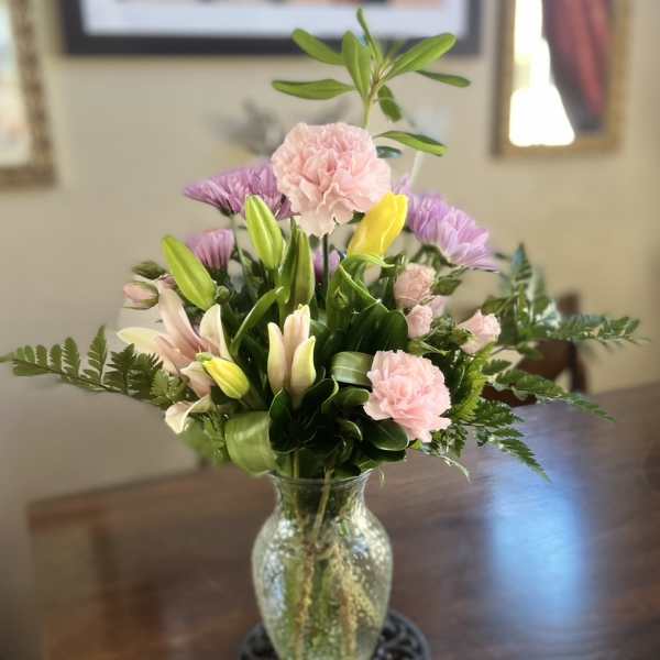 Mixed bouquet of pink and purple flowers in a glass vase