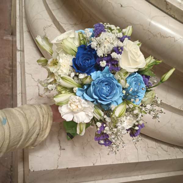 Handheld bouquet of blue, white, and purple roses with small filler flowers