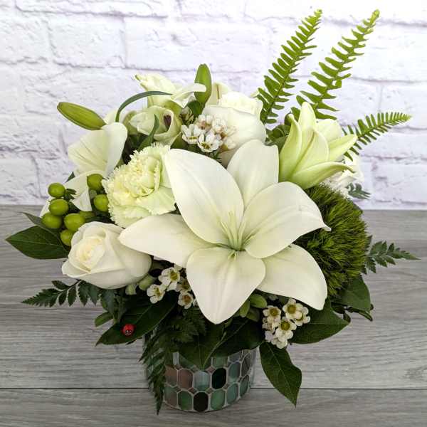 White lilies and roses arranged in a mosaic vase