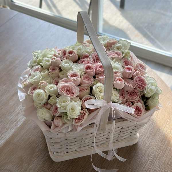 Basket of pink and white roses with a ribbon handle