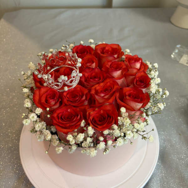 Round arrangement of red roses with white baby's breath and a silver tiara topper