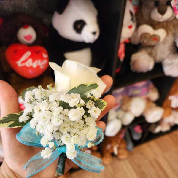 Small white flower boutonniere with blue ribbon
