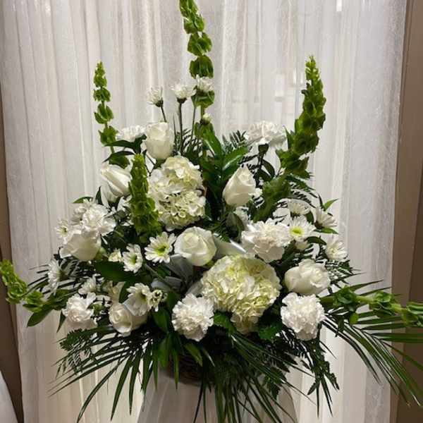 Tall white floral arrangement with roses, hydrangeas, and green spikes