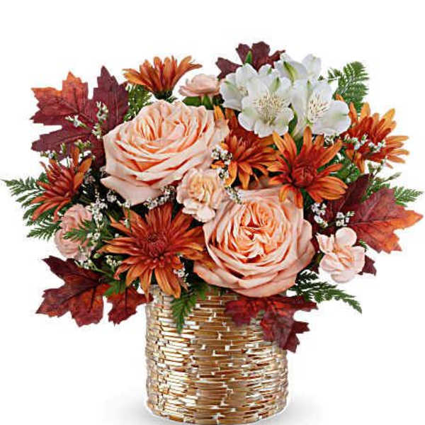 Autumn bouquet of peach roses and orange daisies in a woven basket