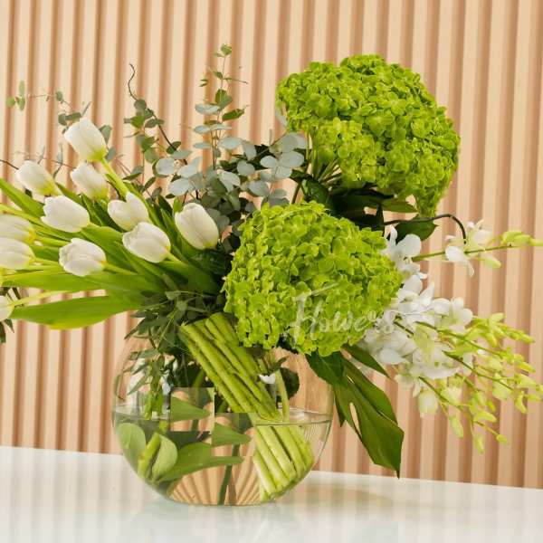 White tulips and green hydrangeas in a clear glass bowl vase
