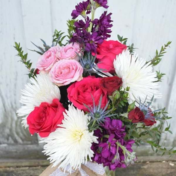 Bouquet of pink and red roses with white daisy-like blooms in a vase